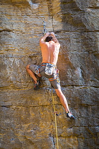 man wearing brown shorts climbing on rock