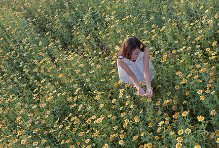 woman wearing white dress standing on daisy flowers field during daytime