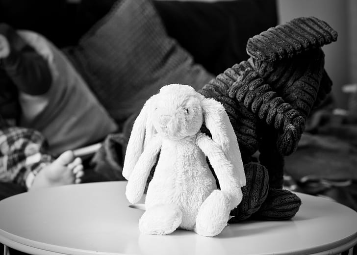 grayscale photography of rabbit plush toy on wooden top table