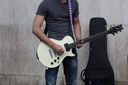 man playing guitar near gray concrete wall