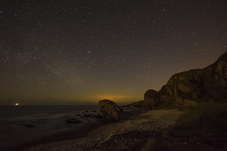 time-lapse photography of brown rock formation under stars