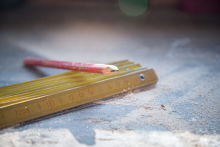 selective focus photography of red pencil on carpenter's ruler