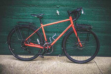 orange and black road bike near green wooden panel