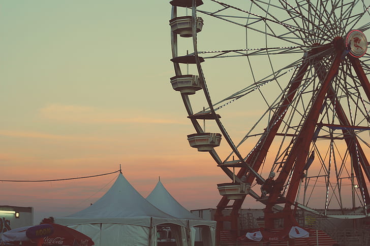 red and white ferris wheel near two white canopy tent during sunset