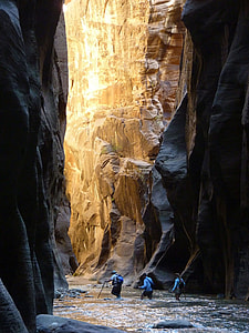 three person inside cave at daytime