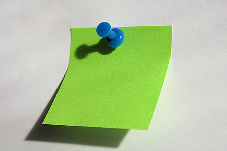green sticky note pinned with push pin