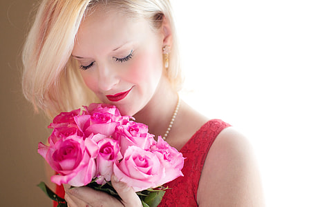 woman wearing red scoop-neck sleeveless top holding bouquet of pink roses