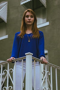 woman wearing blue v-neck long-sleeved shirt and white pants