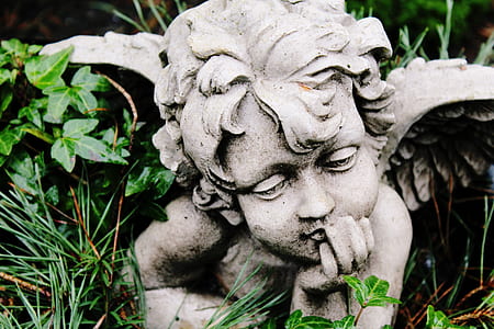 cherub concrete statuette on green grass at daytime