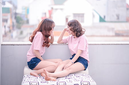two woman wearing matching shirts and shorts sitting on cushion