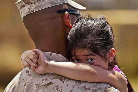 soldier carrying girl wearing pink tank top during daytime