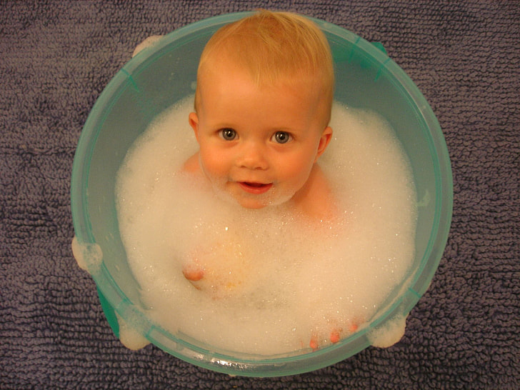 baby inside green plastic bucket filled with bubbles