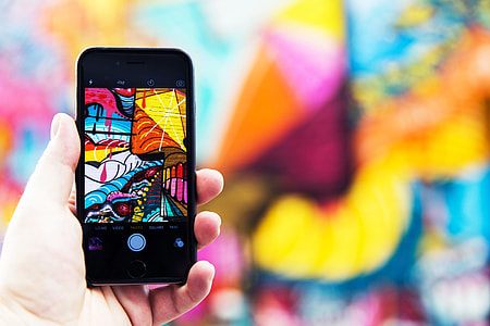 Man photographer capturing street art photo with his hand on iPhone mobile smartphone