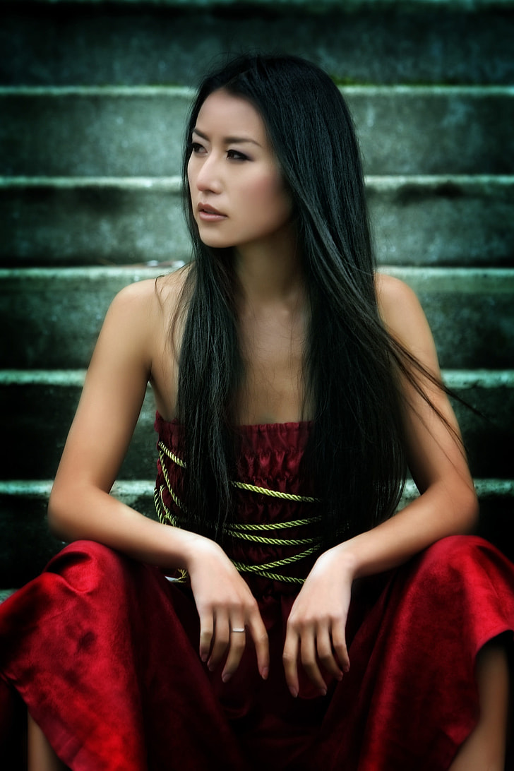 woman wearing red strapless dress sitting on gray concrete stair