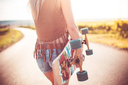 Young Woman Walking on The Road and Holding Longboard