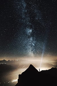 man standing on mountain holding flash lights