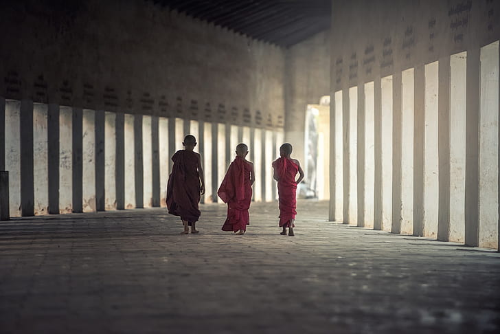 three Buddist monks walking beside each other