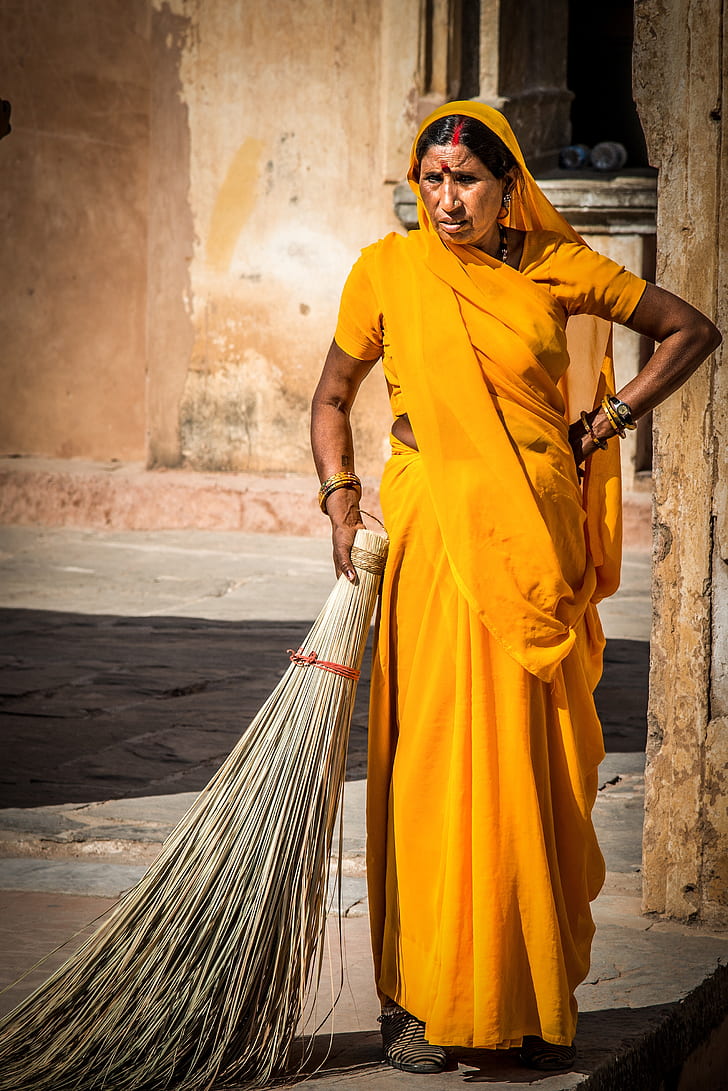 woman in yellow sari dress holding broomstick
