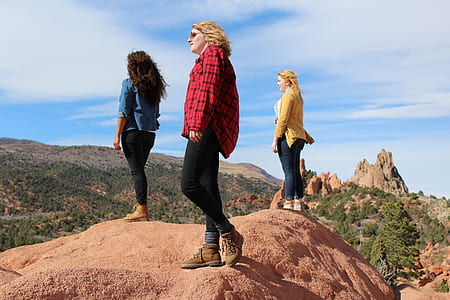 three women standing on mountain cliff during daytime