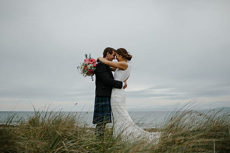 groom and bride on top of grassy hill hugging