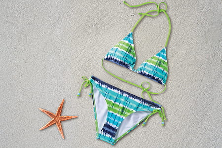 women's blue-and-green halter bikini on beige sand near starfish