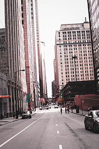 Photo of People Crossing Through Street in the Middle of Buildings