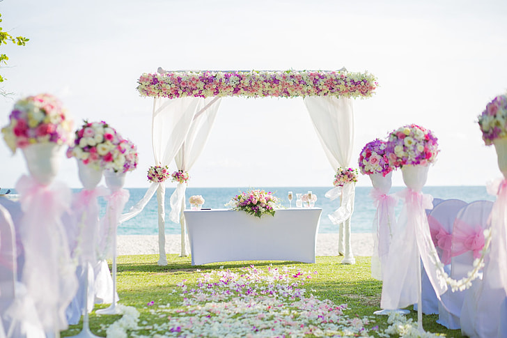 white, pink, and yellow floral wedding arch during daytime