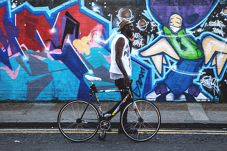 A man with a bicycle walks past vibrant street art in Shoreditch in East London. Image captured with a Canon 6D
