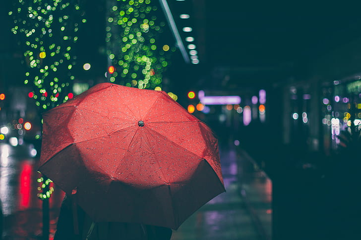 person using red umbrella with bookeh lights photography
