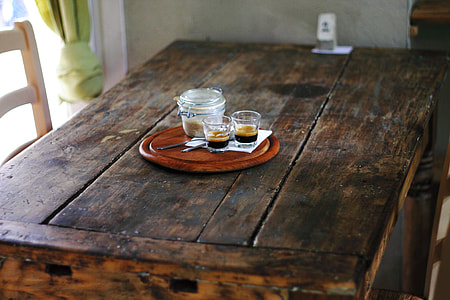 two shot glasses beside mason jar on round brown wooden tray