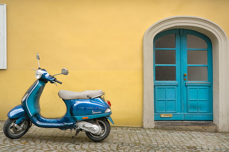 blue motor scooter beside yellow concrete house