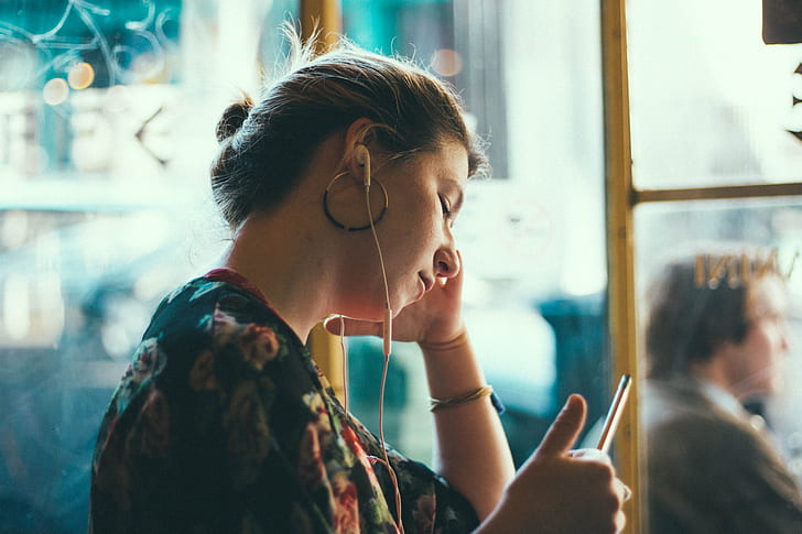 selective focus photography of woman in black and multicolored floral top with white earbuds