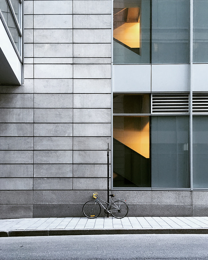 grey bicycle parked near grey concrete building during daytime