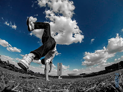 low angle photography of man in white shirt doing cartwheel
