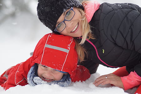 woman wearing black down jacket beside child on snow