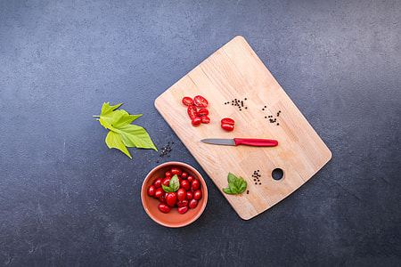 red handed knife beside slice of cherry tomatoes on chopping board