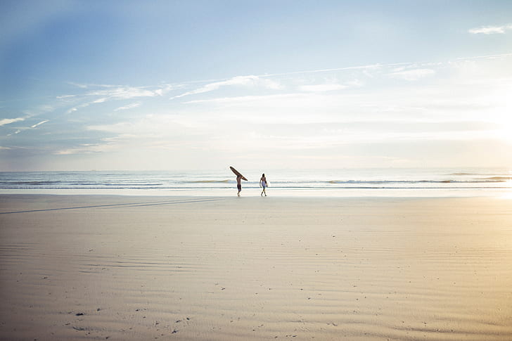 two person standing on front of ocean under blue sky