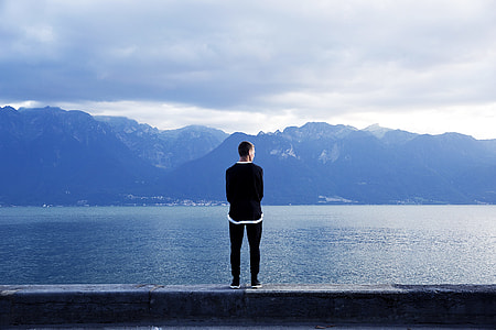 man standing on ledge near body of water