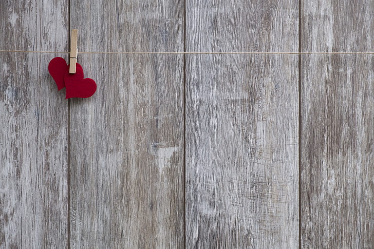 two red heart on string near grey wooden board