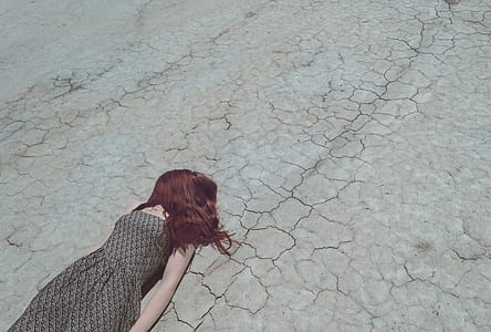person in grey and black sleeveless dress lying on grey concrete road