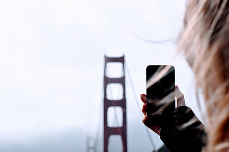 person holding smartphone and facing to Golden Gate Bridge