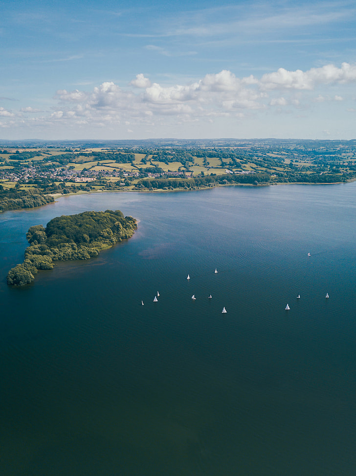 aerial photography of boats sailing near island during daytime