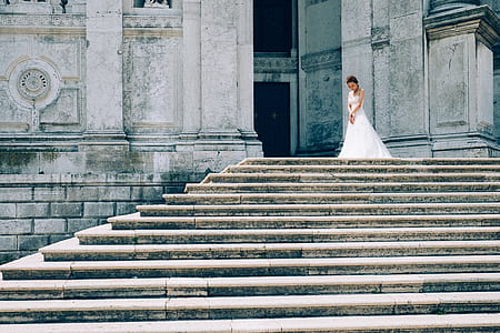 woman wearing white wedding gown standing on top of stairs