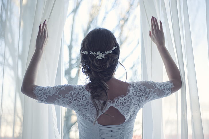 woman wearing white long-sleeved laced top holding white curtains