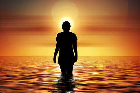 silhouette woman in calm body of water during sunset