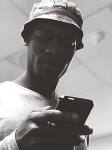 Man in Bucket Hat Holding Black Smartphone