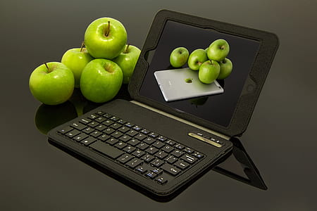 black tablet compute with keyboard besides green apples