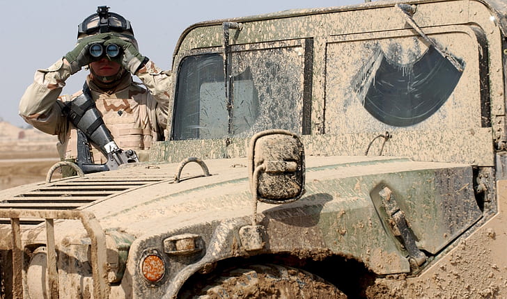 soldier wearing vest holding binoculars standing beside truck
