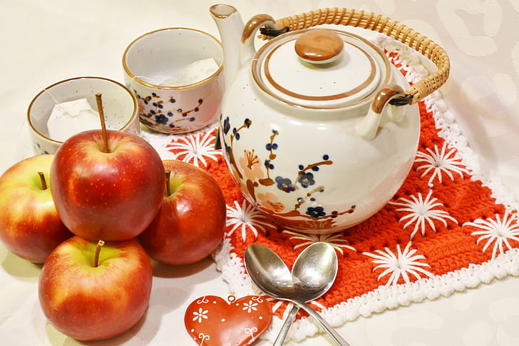 three honeycrisp apples beside white floral teapot and cups