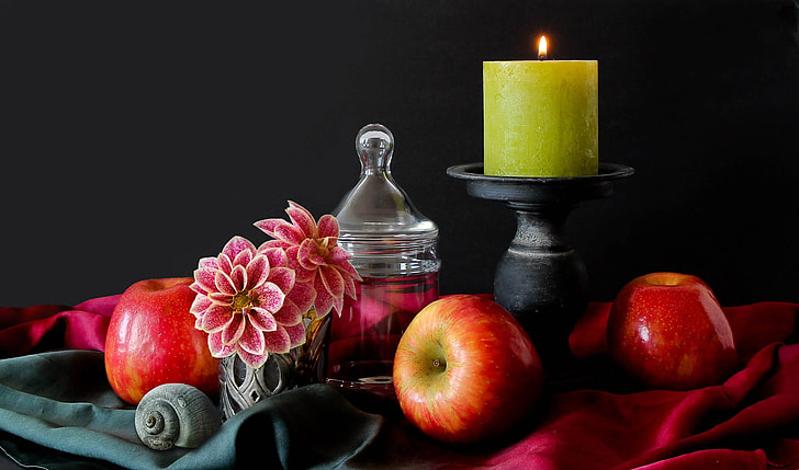 apple beside of black wooden candle holder with green votive candle on top table